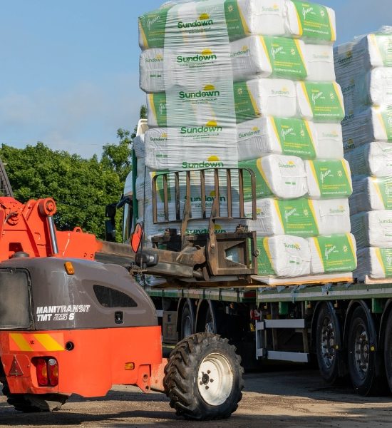 A forklift truck unloads a pallet of Sundown Green bedding bales from a lorry