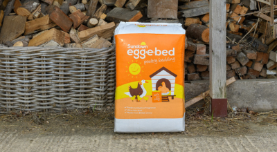 Egg-e-bed bale in front of woodpile