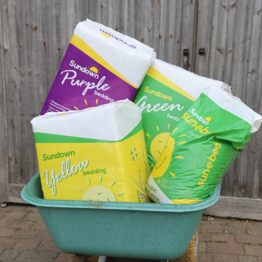 Bales of Sundown bedding in a green wheelbarrow